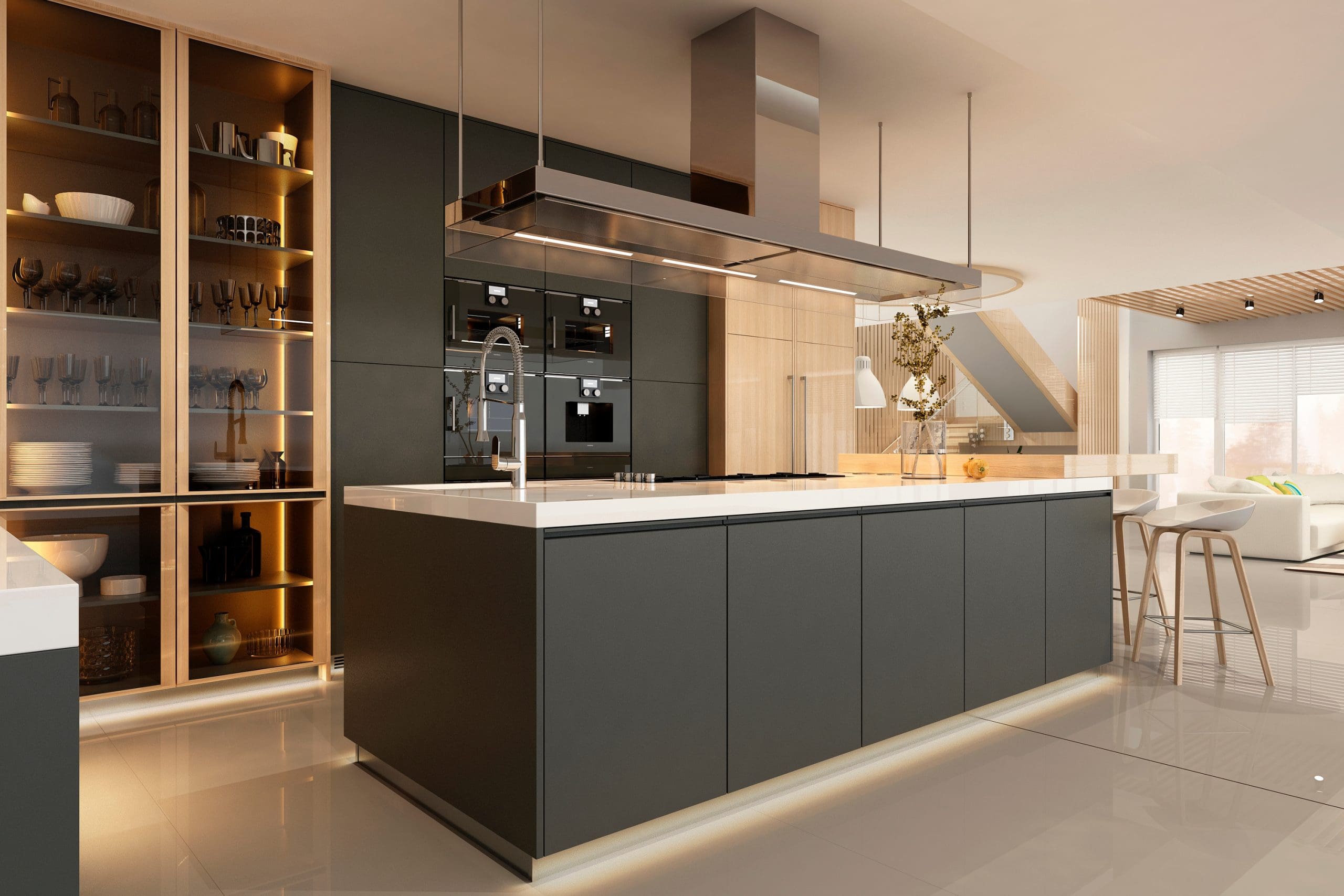 A modern kitchen featuring a large island with a built-in sink and stovetop, sleek dark cabinetry, and stainless steel appliances. A glass-fronted display cabinet with illuminated shelves is on the left. The background shows an open living area with large windows.